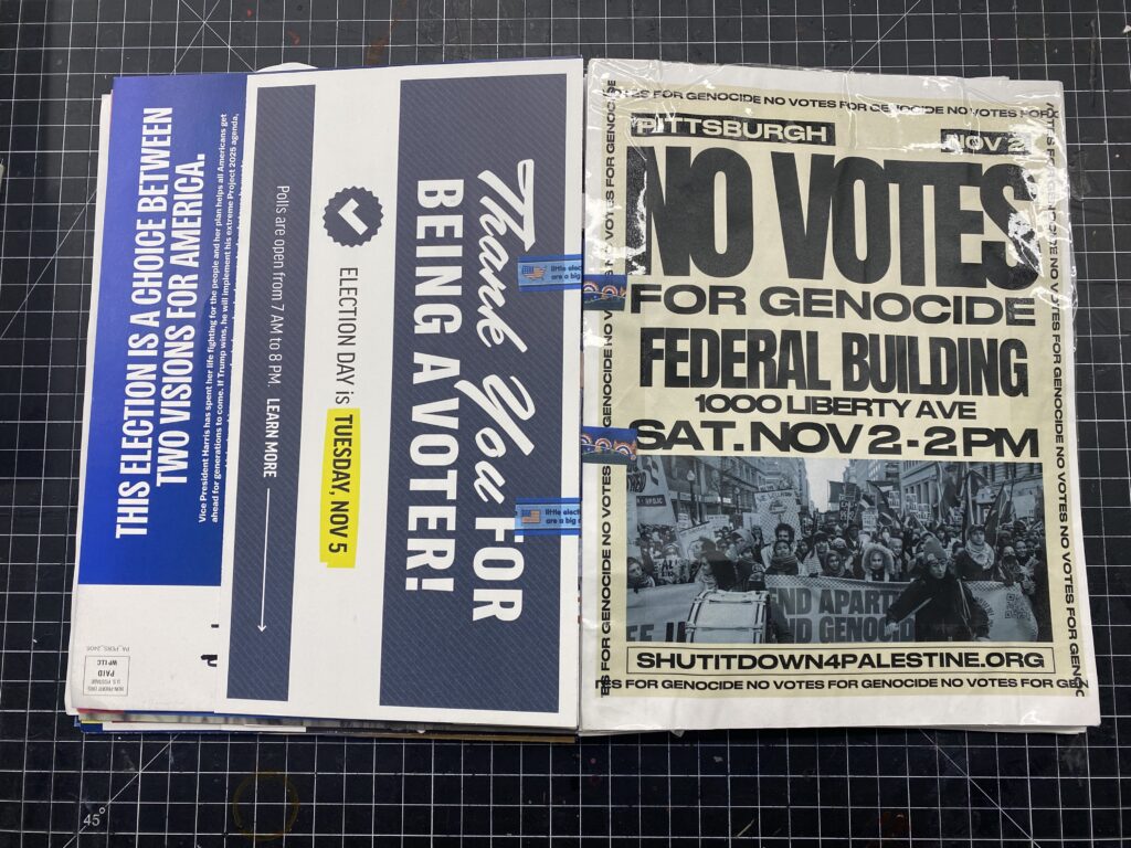 The book held open on a tab that shows a poster for No Votes for genocide and the back of a mailer that says Thank You For Being a Voter.