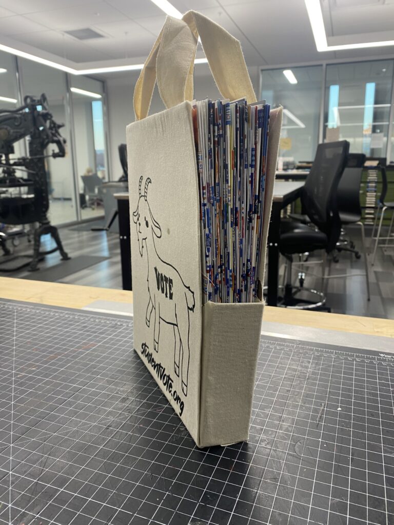 The fully assembled book in its box bag,  showing the intricate tab bind facing the camera. 