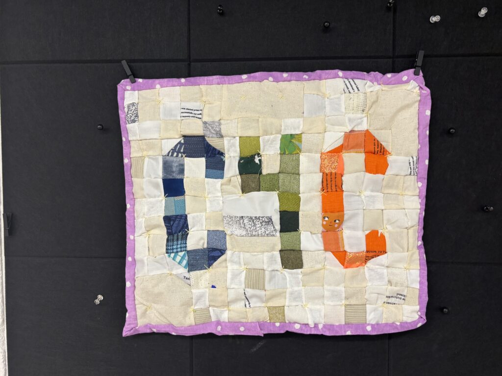On a flat surface a quilt that reads C4C in pixelated font.